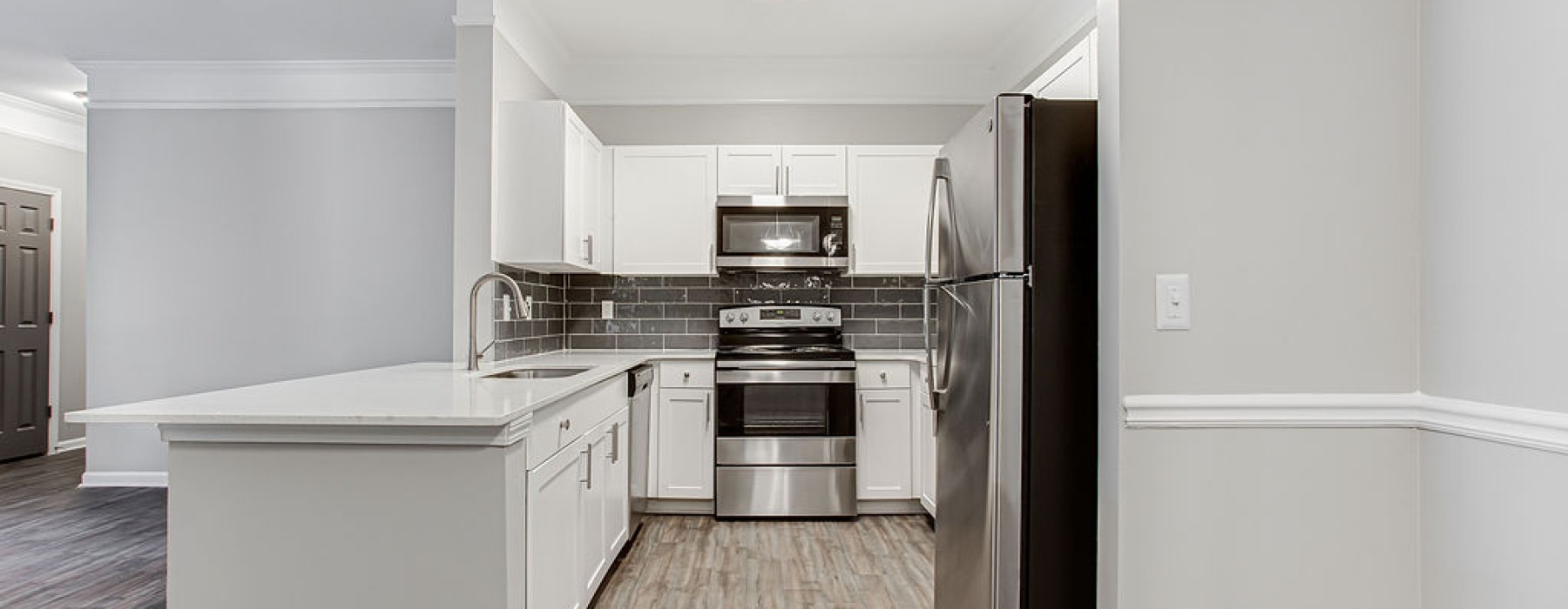 Kitchen with vinyl plank flooring, granite countertops, white shaker cabinets, and stainless steel appliances