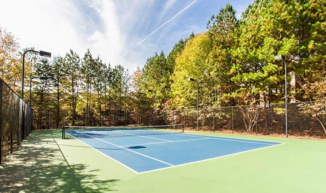 A beautiful community at the heart of all your passions a tennis court with trees on the side